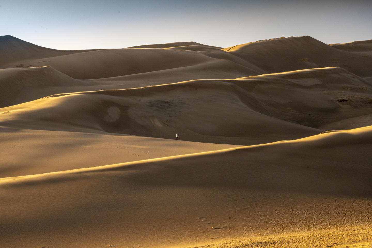 Late afternoon shadows in Great Sand Dunes National Park. The person in the center of the frame provides a sense of scale to this powerful landscape. #greatsanddunesnationalpark #orcuttphotography.com #sprintervantookusthere #sanddunes #southerncolorado #nationalparksystem #lightandshadows