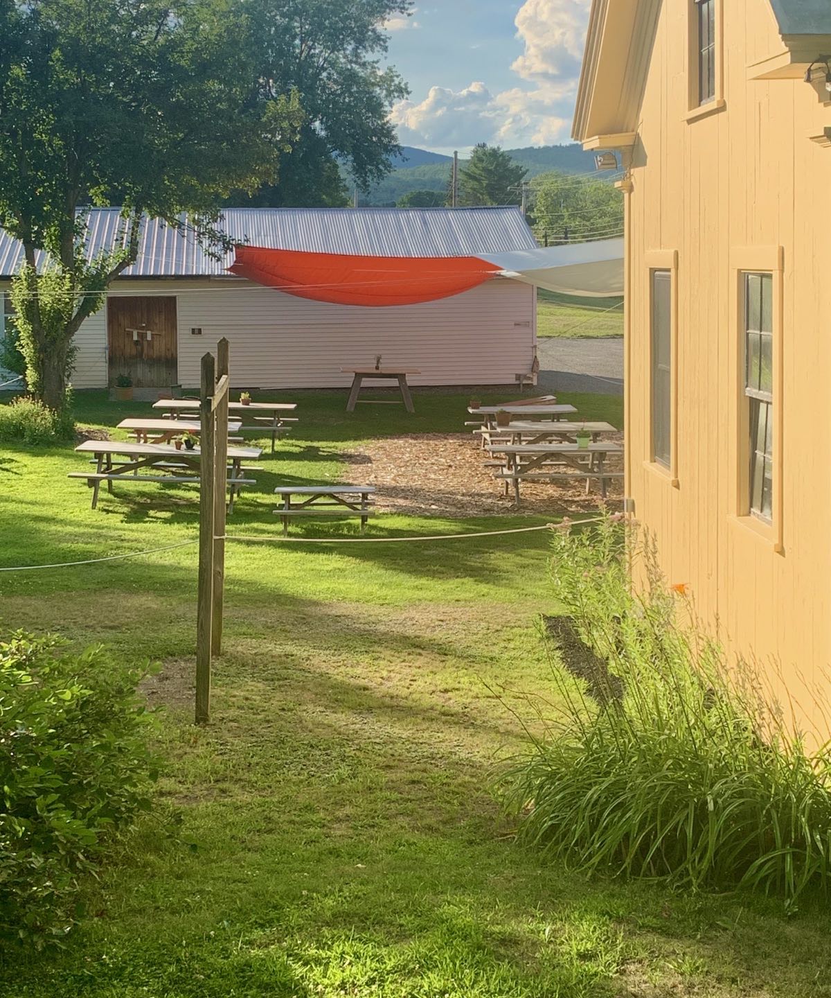 Rolling Fatties Backyard Sniki Bar is the view from our front porch on a quiet Monday evening. The red sun shade is a great burst of color for this enjoyable community space in Kingfield, Maine. #rollingfatties #kingfieldmaine #orcuttphotography #backyardbar